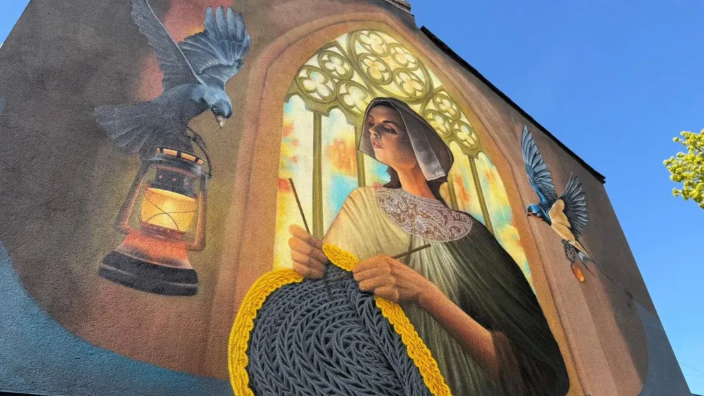 Murale di Sam Porter a Bridlington con la Gansey Girl, figura femminile della tradizione marinara, circondata da uccelli e simboli del folklore locale.