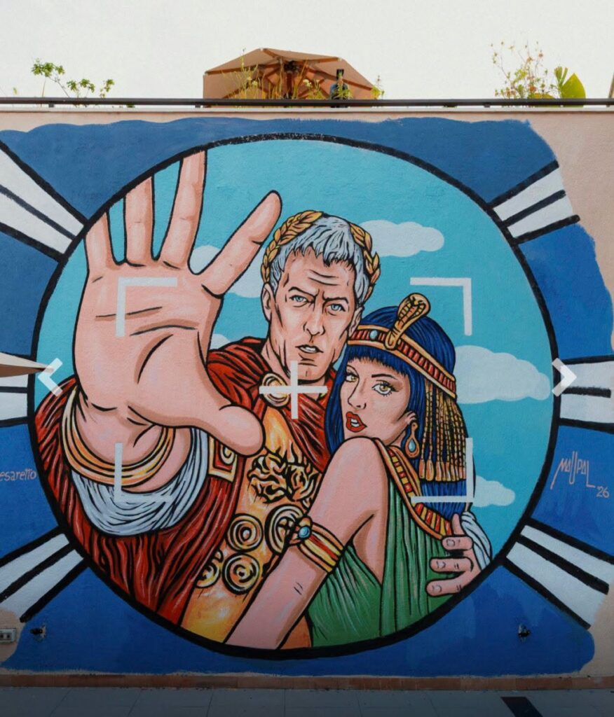 Murale Cleo e Cesaretto di Maupal al Paparazzo Bar & Rooftop di Roma, con Cleopatra e Giulio Cesare in posa davanti a un obiettivo fotografico