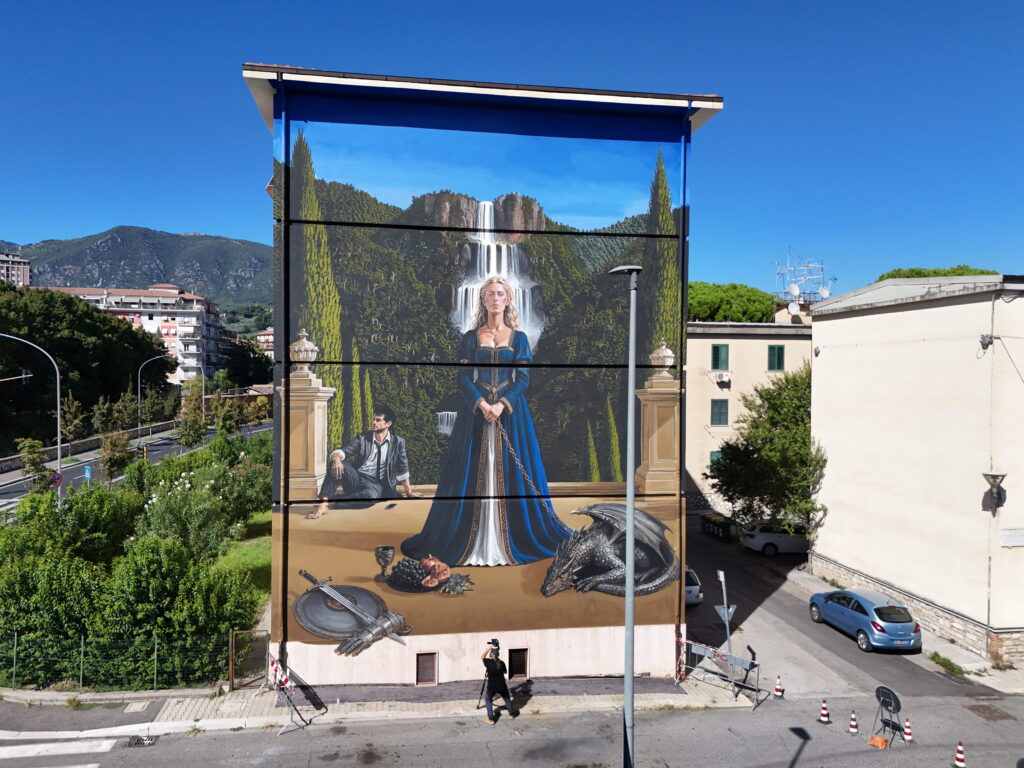 Dettaglio del murale di OZMO a Terni, con una donna in abito blu raffigurata davanti alla Cascata delle Marmore.